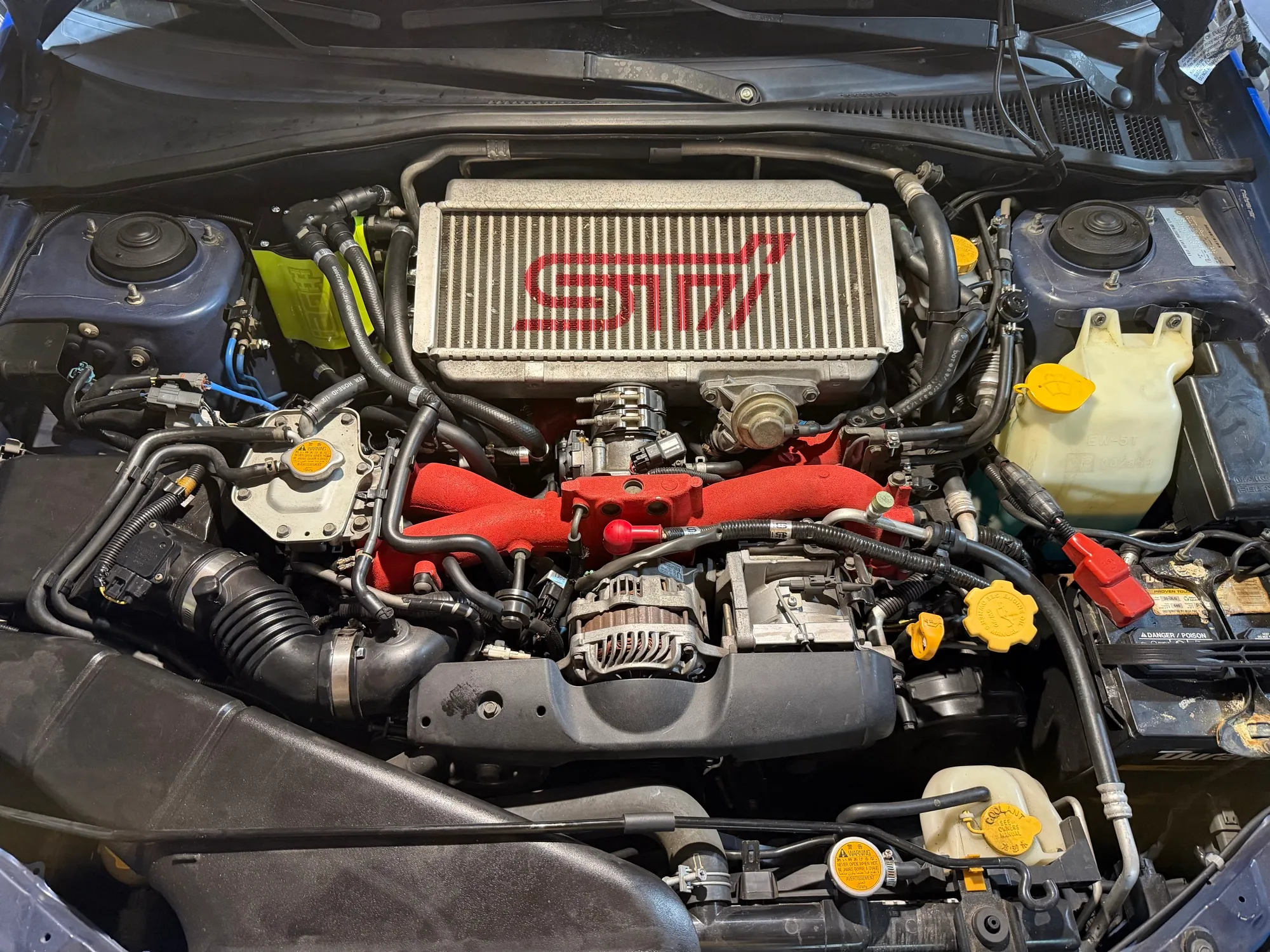 The finished engine bay with the intercooler and throttle body reinstalled, the green AOS just visible at the left edge of the bay.